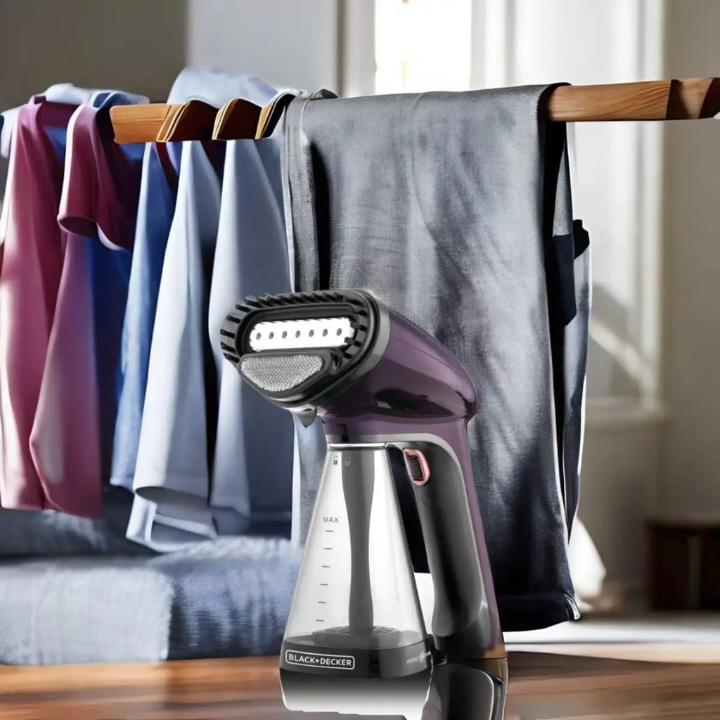 Handheld steamer on a wooden surface with clothes hanging in the background