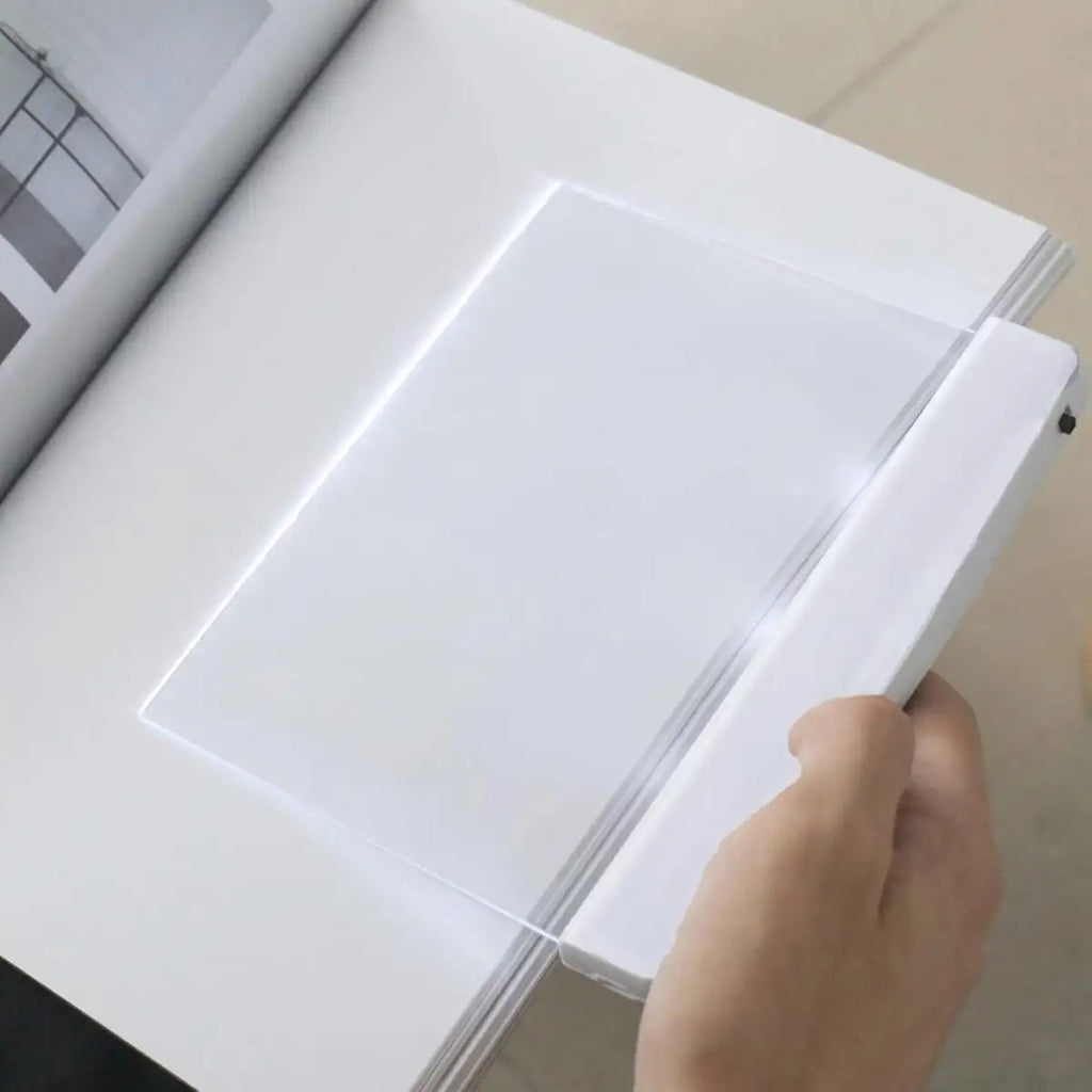 Hand opening a white book with a light on a neutral background