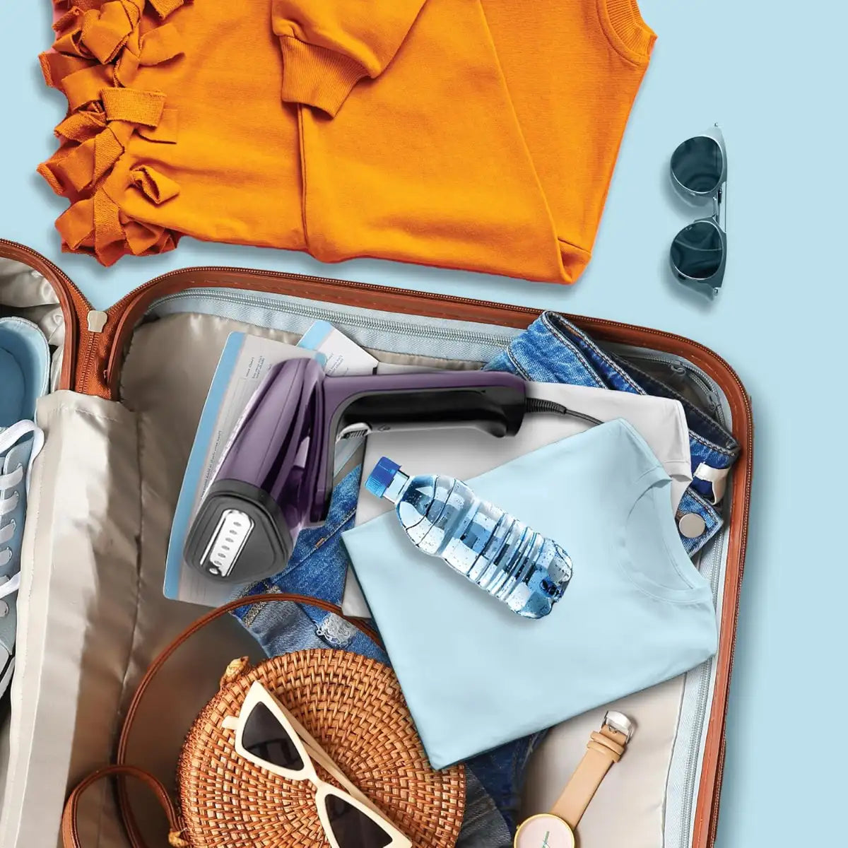 Open suitcase with travel items including an orange shirt, sunglasses, a water bottle, and a watch on a light blue background.