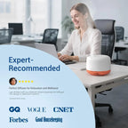 Woman using a laptop in an office with a diffuser on the desk, surrounded by credibility badges.